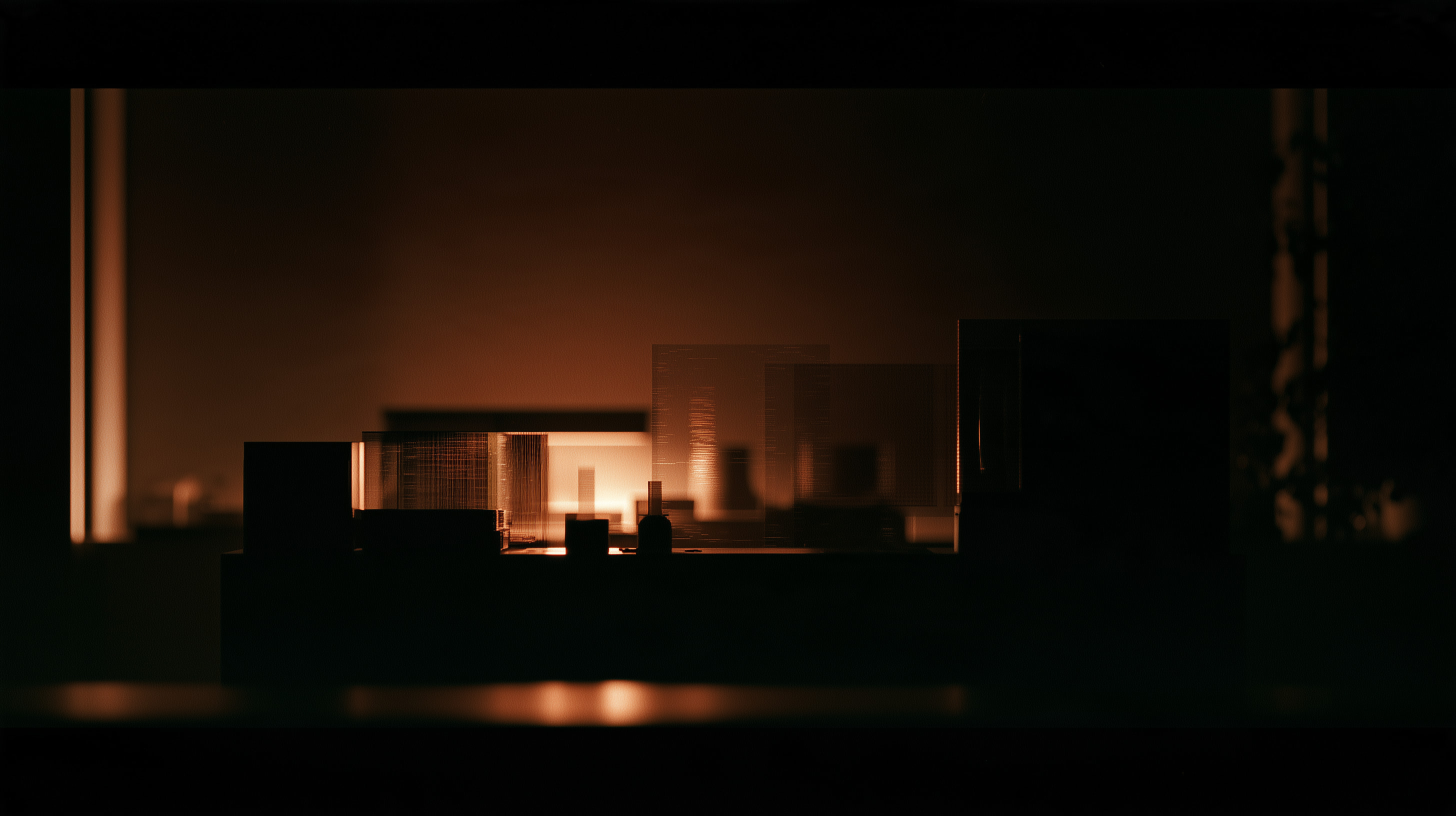 Architectural model on a desk in a dark room, lit by a low orange glow